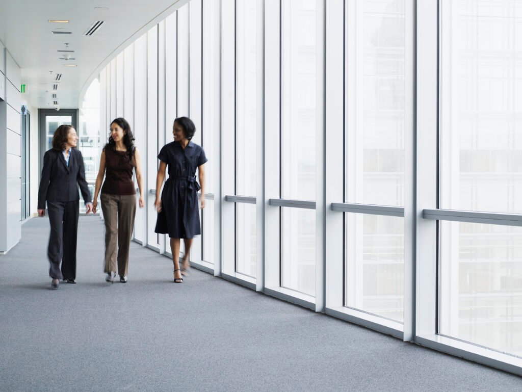 Communication, fluidité businesswomen walking in hallway, smiling, portrait